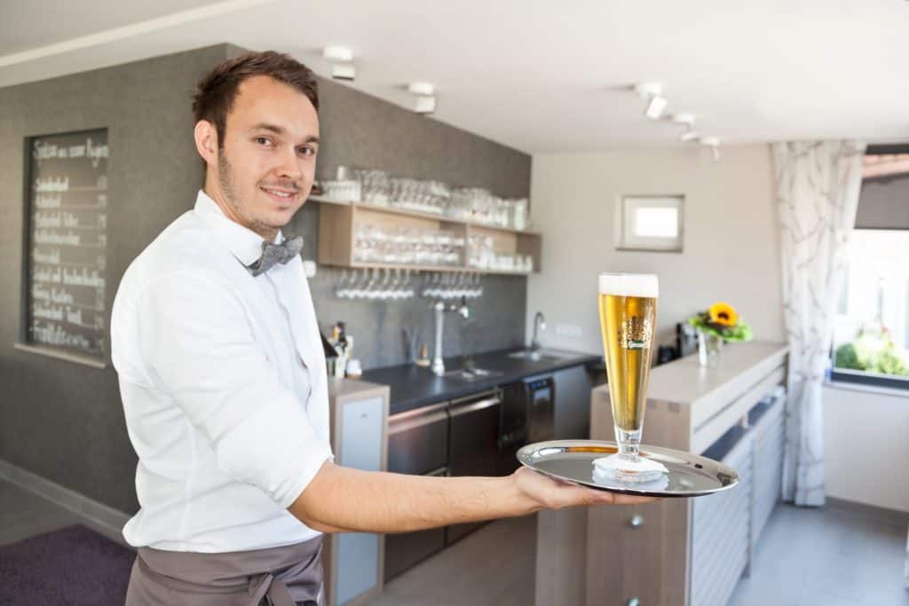 Birkenhof Lounge mit Kellner der ein Bier auf einem Tablett hält